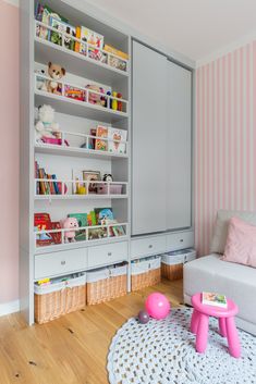 a child's room with pink and white striped wallpaper, bookshelves and toys