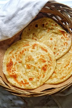 four flat breads in a basket on a table