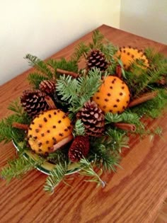 some pine cones sitting on top of a wooden table with green plants and pine cones