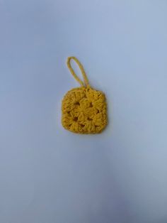 a crocheted square ornament hanging from a hook on a white surface