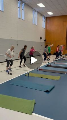 a group of people riding skateboards on top of a blue mat in a gym