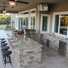 an outdoor kitchen with bar stools and grill