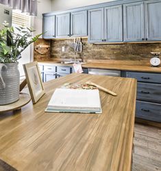 a kitchen with blue cabinets and wooden counter tops, an open book on the table