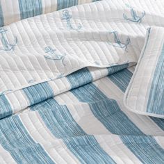 an unmade bed with blue and white striped sheets