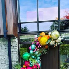 a wreath made out of balloons and palm leaves on the side of a building in front of a door