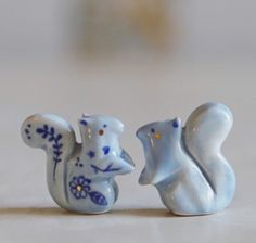 two small ceramic squirrel figurines sitting next to each other