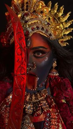 a woman with makeup and elaborate headdress holding a knife in her hand,