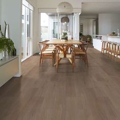 a large dining room with wooden floors and white walls, along with lots of windows