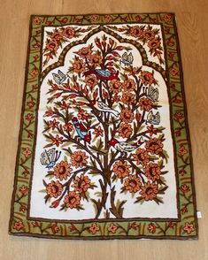 a tree with birds and flowers is on the floor in front of a wall hanging