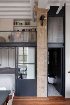 a bedroom with a loft bed next to a kitchen and living room in the background