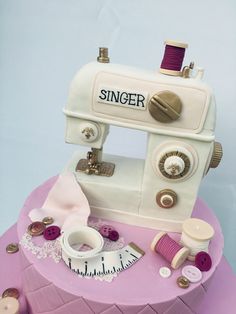 a cake made to look like a sewing machine on top of a pink tablecloth