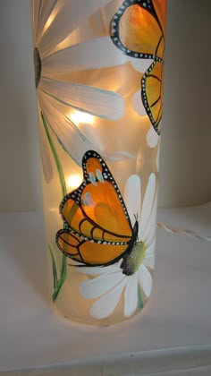 a glass vase with butterflies painted on it and lights in the bottom, sitting on a table