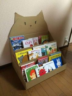 a cardboard box filled with books sitting on top of a wooden floor next to a wall