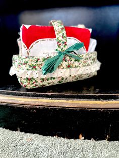 an old fashioned basket sitting on top of a black table next to a red and white pillow