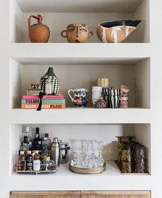 the shelves in this kitchen are filled with dishes and vases on top of them