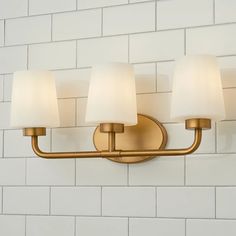 three light bathroom fixture with white shades on brick wall in residential home setting, closeup