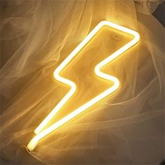 a neon sign that is sitting on top of a white cloth covered bed sheet,