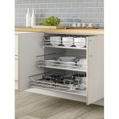 an open cabinet in a kitchen with dishes and utensils on the bottom shelf