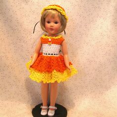 the doll is wearing a dress made from crochet and has a yellow headband