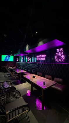 an empty restaurant with tables and chairs lit up by neon lights in the dark room