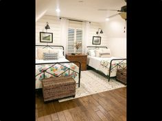 two beds in a room with wooden floors and white walls, one has a basket on the floor