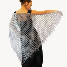 a woman is wearing a shawl made from crocheted yarn and has her hands on her hips