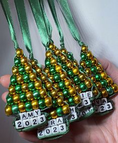 a person holding some christmas ornaments in their hand with green and gold beads on them