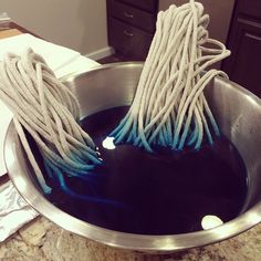 two mop heads in a metal bowl with blue liquid