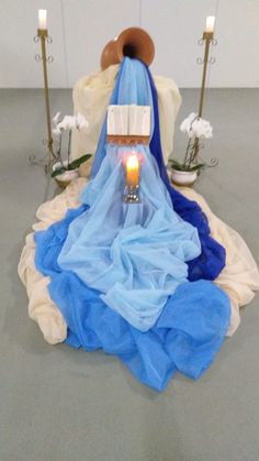 a blue and white dress sitting on top of a floor next to two lit candles