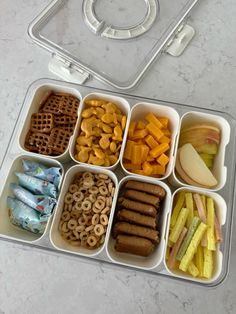 an open lunch box filled with different types of snacks and apple slices on the side