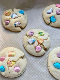 six cookies with pastel hearts and candy on them sitting on a baking sheet, ready to be baked