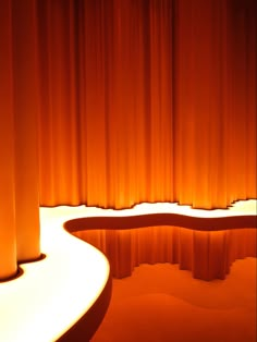 an orange curtained stage with light shining on the floor and curtains in the background