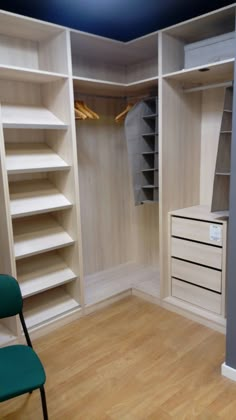 an empty walk - in closet with white shelves and green chair next to the door