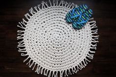 a white and blue placemat with tassels sitting on a wooden table top