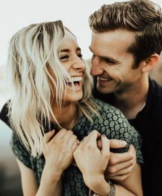 a man and woman smile as they hold each other