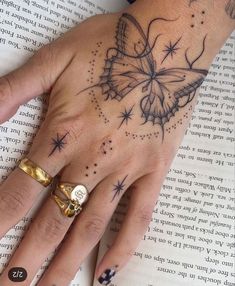 a woman's hand with a butterfly tattoo on it, and an open book