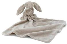 a stuffed animal sitting on top of a white blanket covered in a light gray blanket