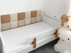 there is a white bed with pillows and a stuffed animal next to the bed headboard