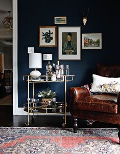 a living room filled with furniture and pictures hanging on the wall behind a leather chair