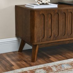 a wooden cabinet sitting on top of a hard wood floor next to a white rug