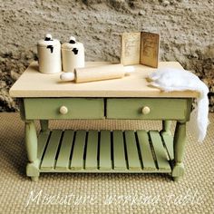 a green table with two drawers and some books on it next to a rock wall