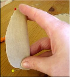 a hand is holding an object on a wooden table with pins and needles in it