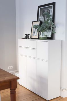 a white cabinet with some plants on top