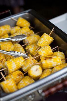 corn on the cob with tongs and toothpicks in a metal container