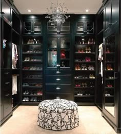 a walk - in closet with black cabinets and chandelier