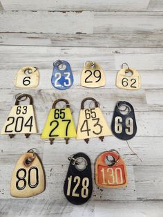 an assortment of numbered key tags hanging from hooks on a white wooden wall with numbers