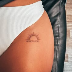 the back of a woman's stomach with a small sun tattoo on her left side