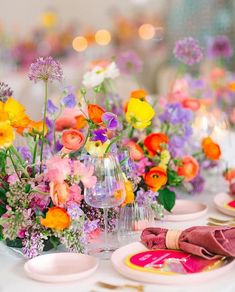 the table is set with colorful flowers and wine glasses for an elegant dinner party or celebration