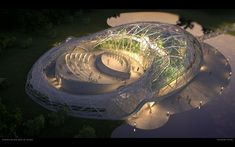 an aerial view of a circular building in the middle of a park at night with people walking around it