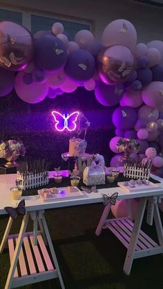 a white table topped with lots of purple balloons and desserts on top of it